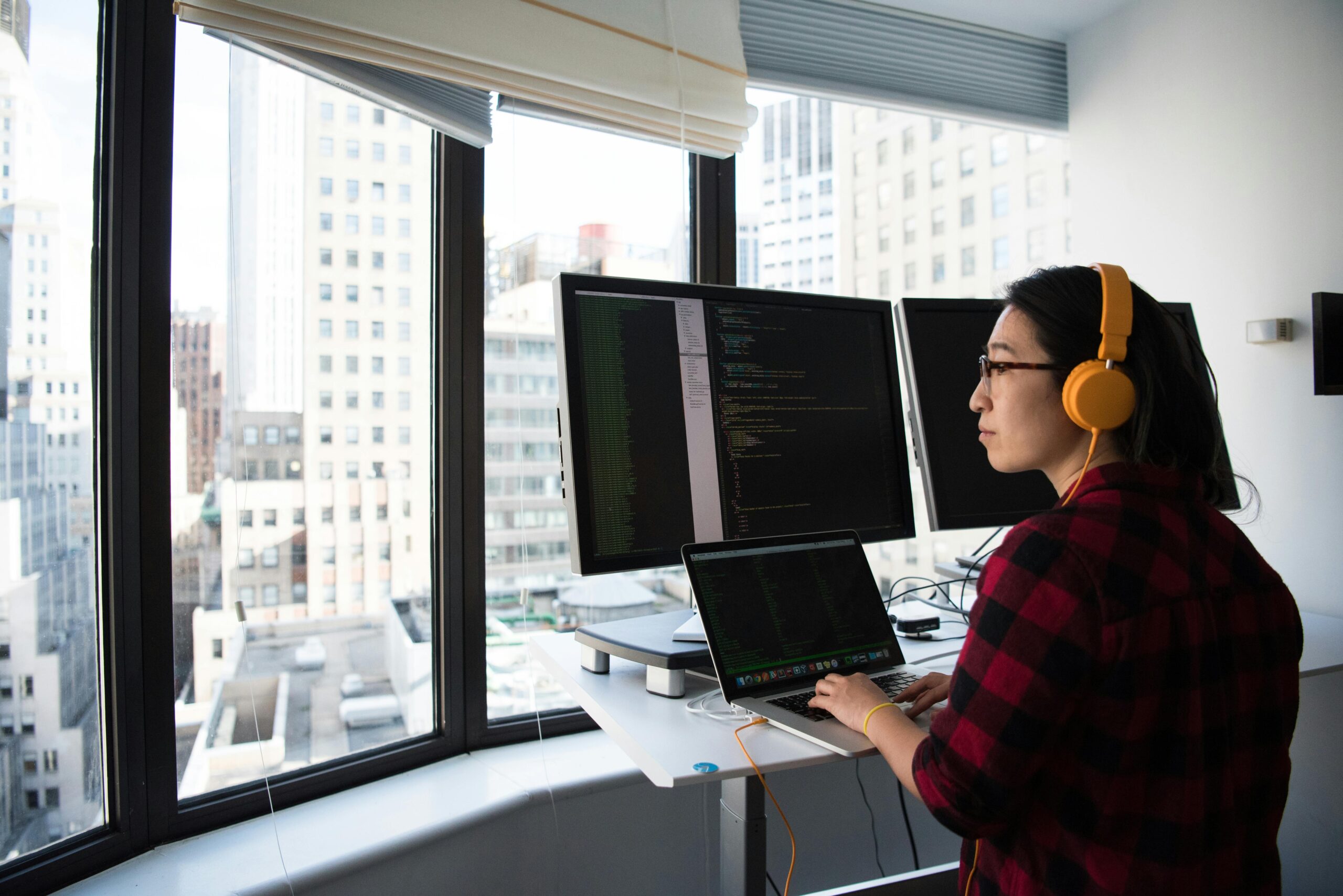 Young woman coding custom healthcare software looking out window